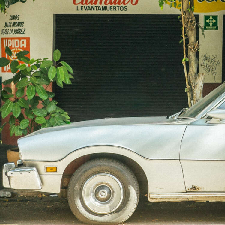 Vintage car parked outside a clamato bar in Condesa, Mexico City, photographed in soft cinematic light with analog film inspired tones.
