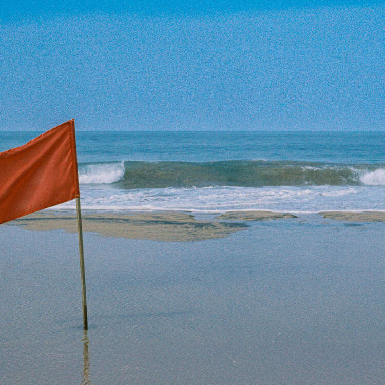 Sri Lanka beach photography print featuring a red warning flag beside ocean waves shot on Kodak Gold film.