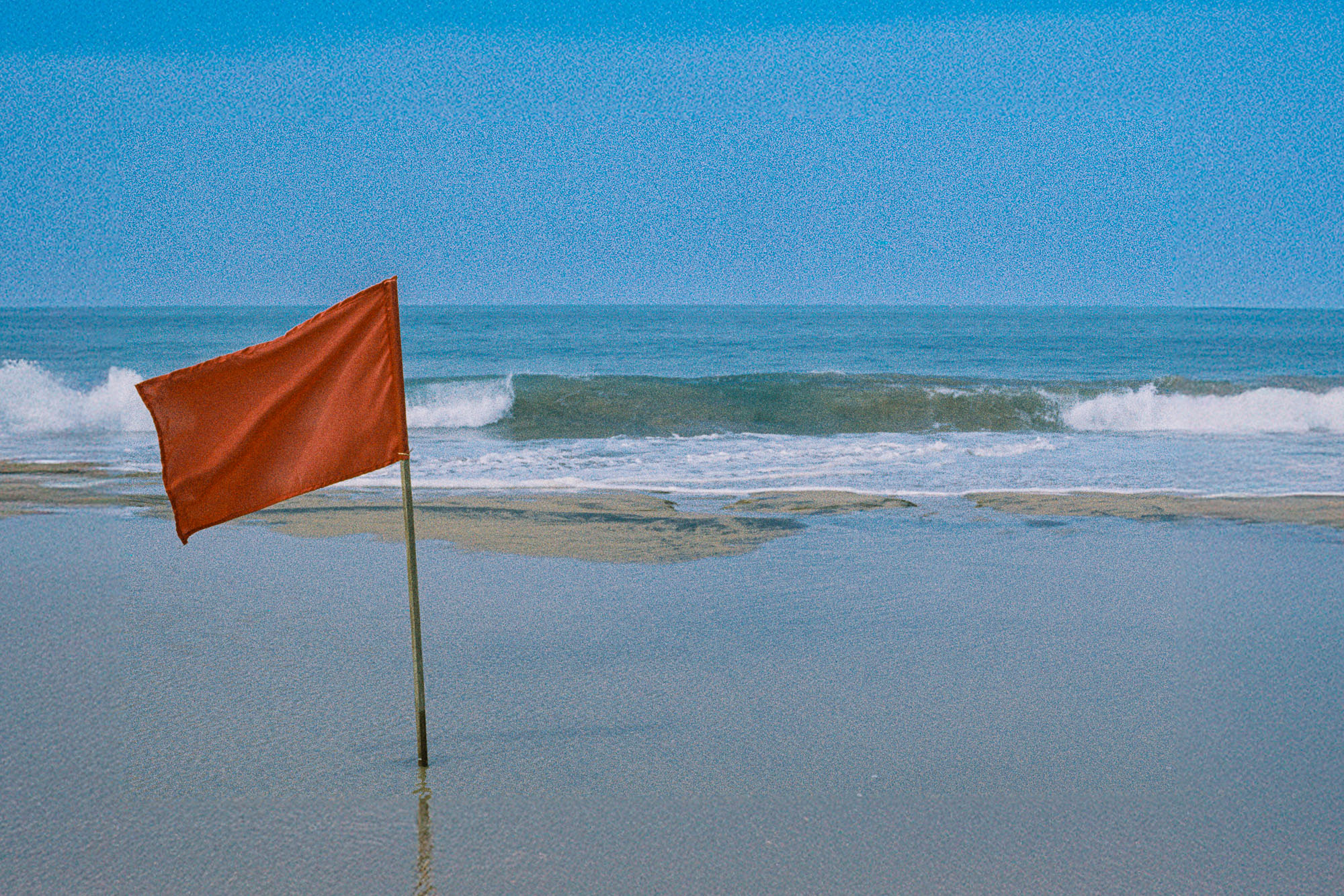 Sri Lanka beach photography print featuring a red warning flag beside ocean waves shot on Kodak Gold film.